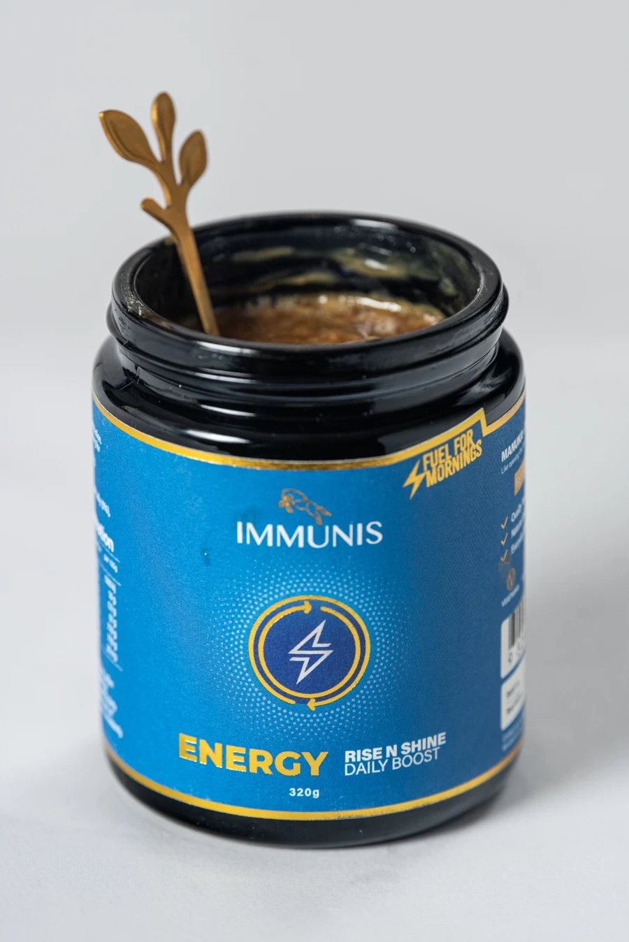 An open Immunis Energy jar with a golden spoon